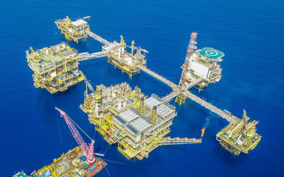 Offshore production complex of bridge-linked platforms with cranes, seen from the air in open water