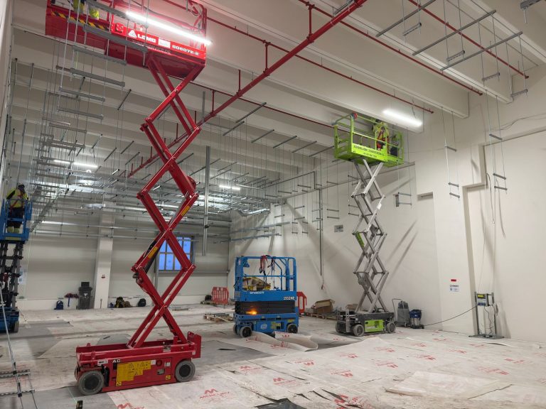 RAM project: Crews on red and green scissor lifts fitting ceiling mounted containment supports