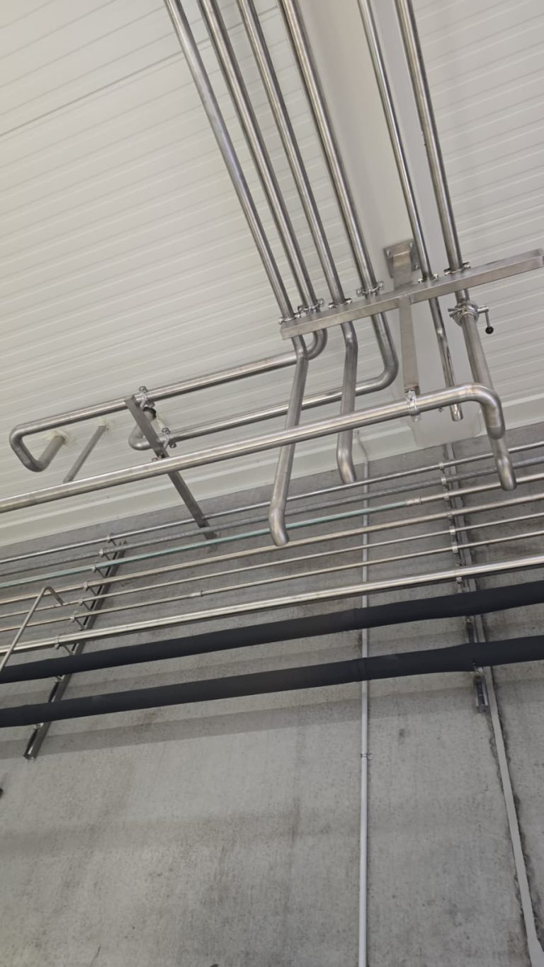 RAM project: Detail of parallel stainless steel pipes and ceiling supports in the brewery