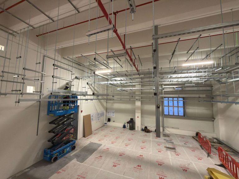 RAM project: Installer on a blue scissor lift beside overhead cable trays in Frankfurt