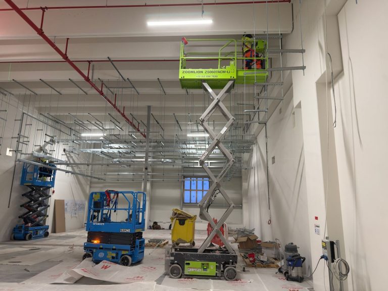 RAM project: Installer on a raised green platform beside suspended cable ladder supports