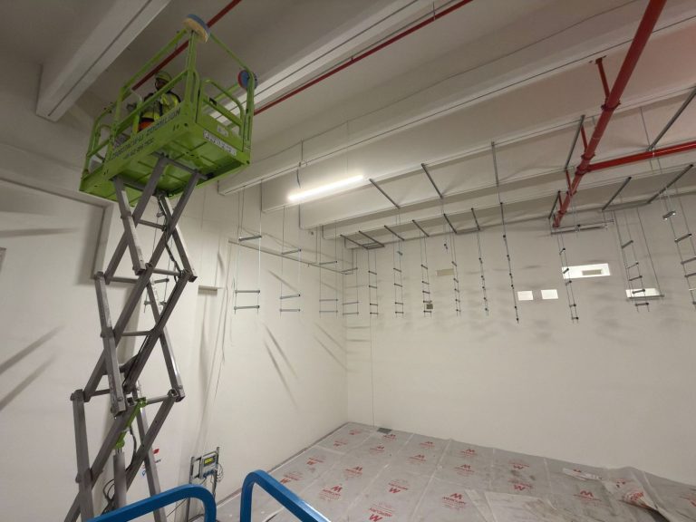 RAM project: Installer working near ceiling level from a green scissor lift