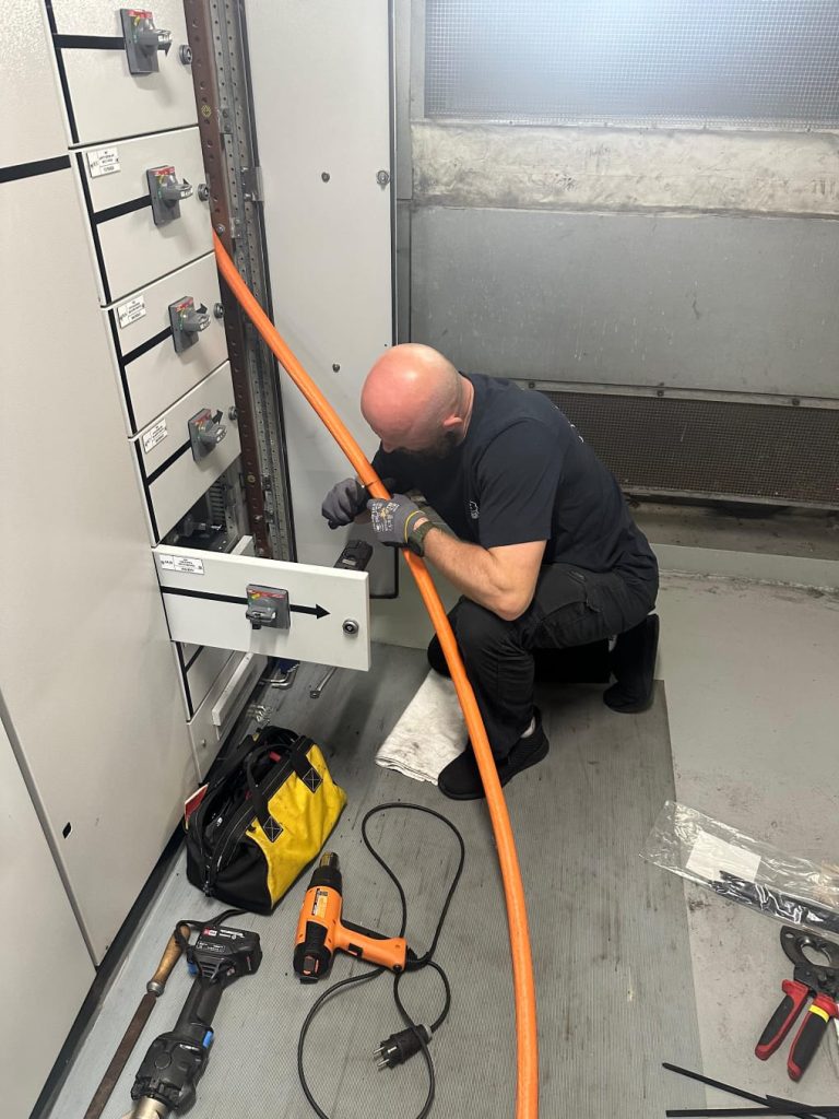 RAM project: Marine electrician preparing a power cable beside a ship switchboard