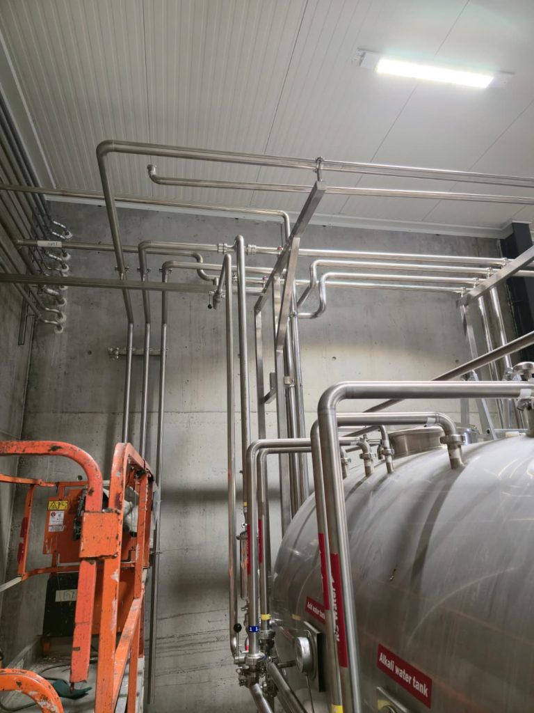 RAM project: Overhead stainless steel pipe routes connected to brewery water tanks in Denmark