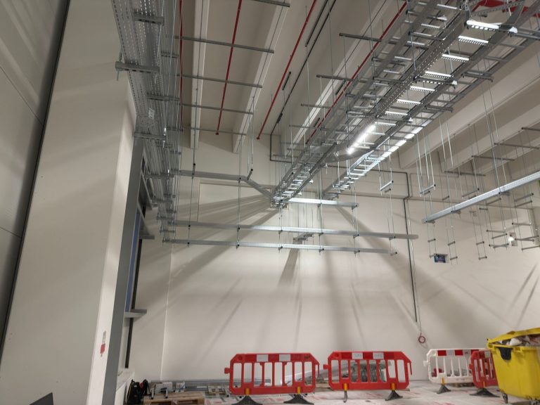 RAM project: Parallel suspended cable trays and ladder routes above a cordoned work area