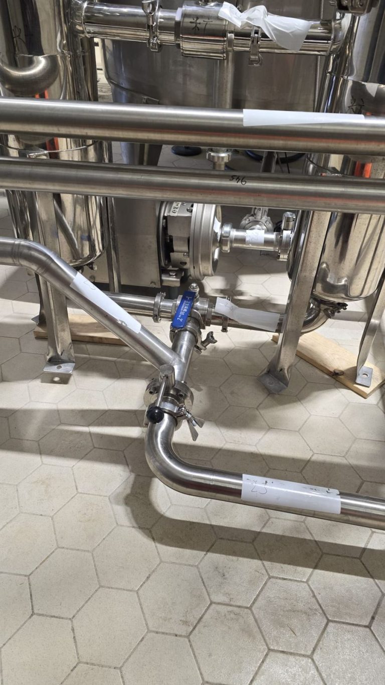 RAM project: Pump, valves and stainless steel pipe bends below brewery filtration equipment