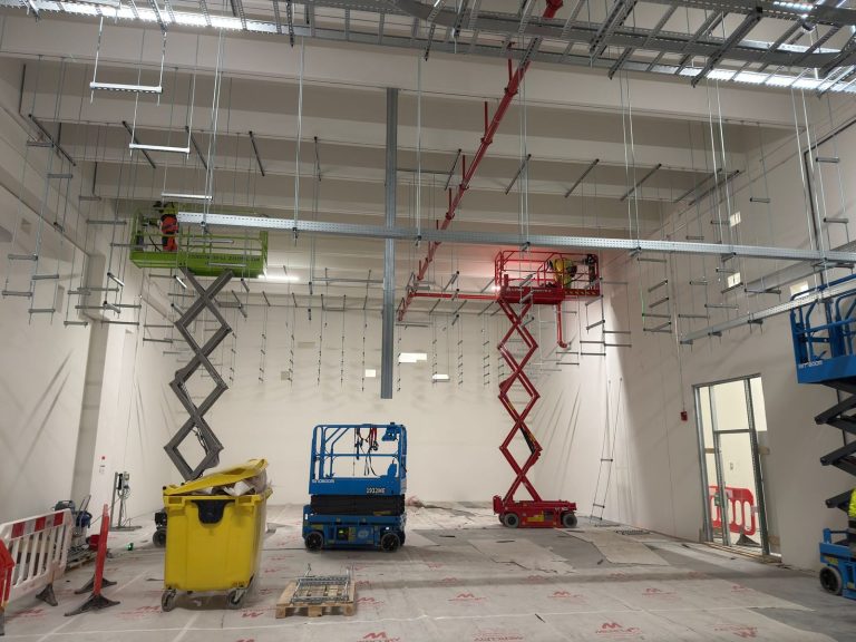 RAM project: Raised red and green scissor lifts beneath cable containment installation in Frankfurt