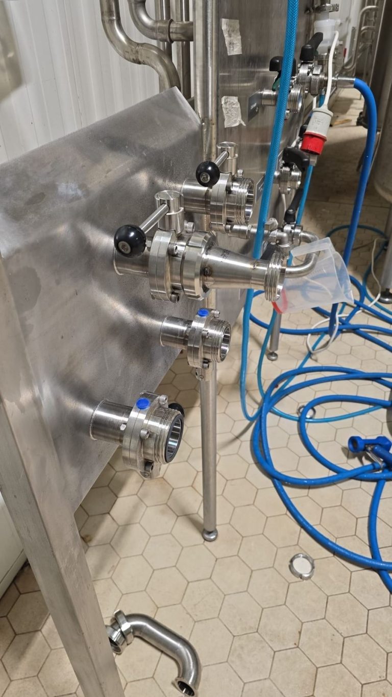 RAM project: Stainless steel tank connections and manual valves with blue hoses at the brewery