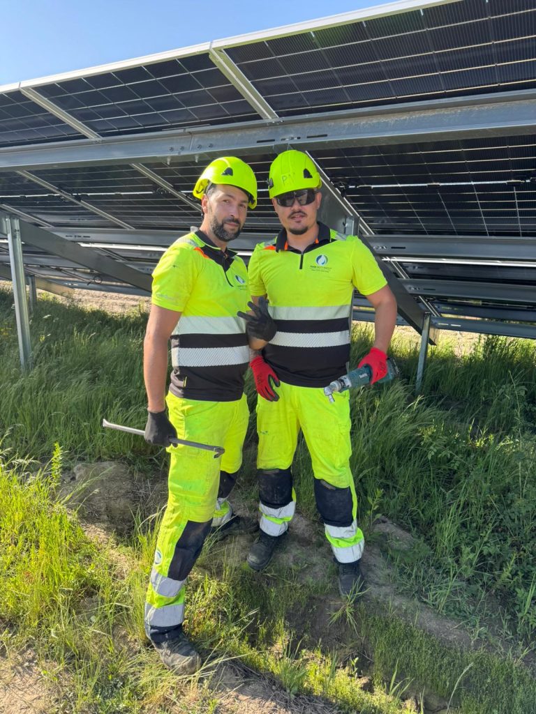 Two RAM workers beside solar panel mounting structures