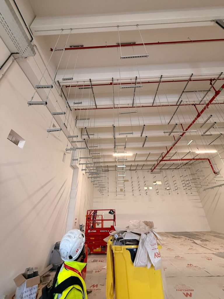 RAM project: Worker looking toward suspended support brackets during containment installation